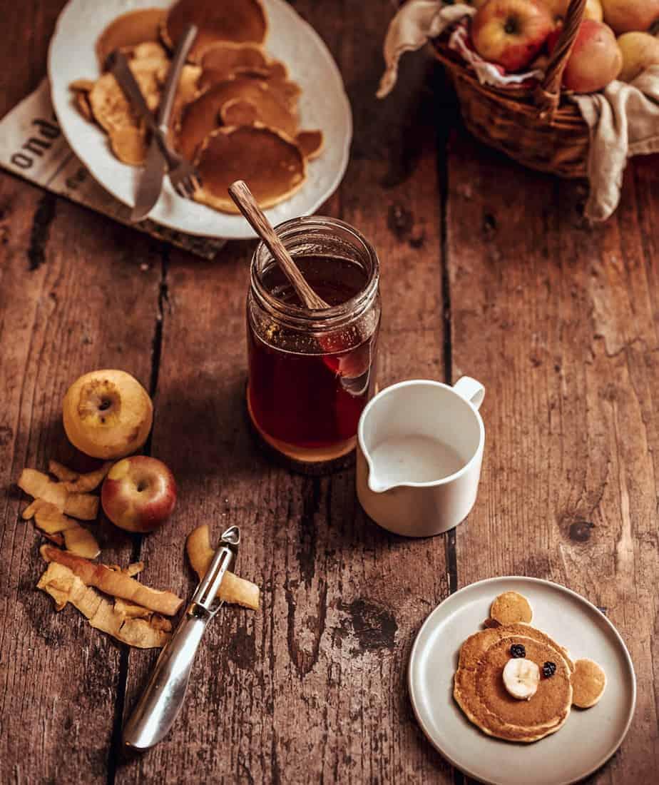 A rustic wooden table with a baked apple crisp and mugs of tea