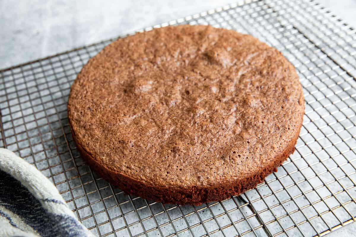 overhead shot of a golden brown almond flour chocolate cake cooling on a wire rack, steam gently rising