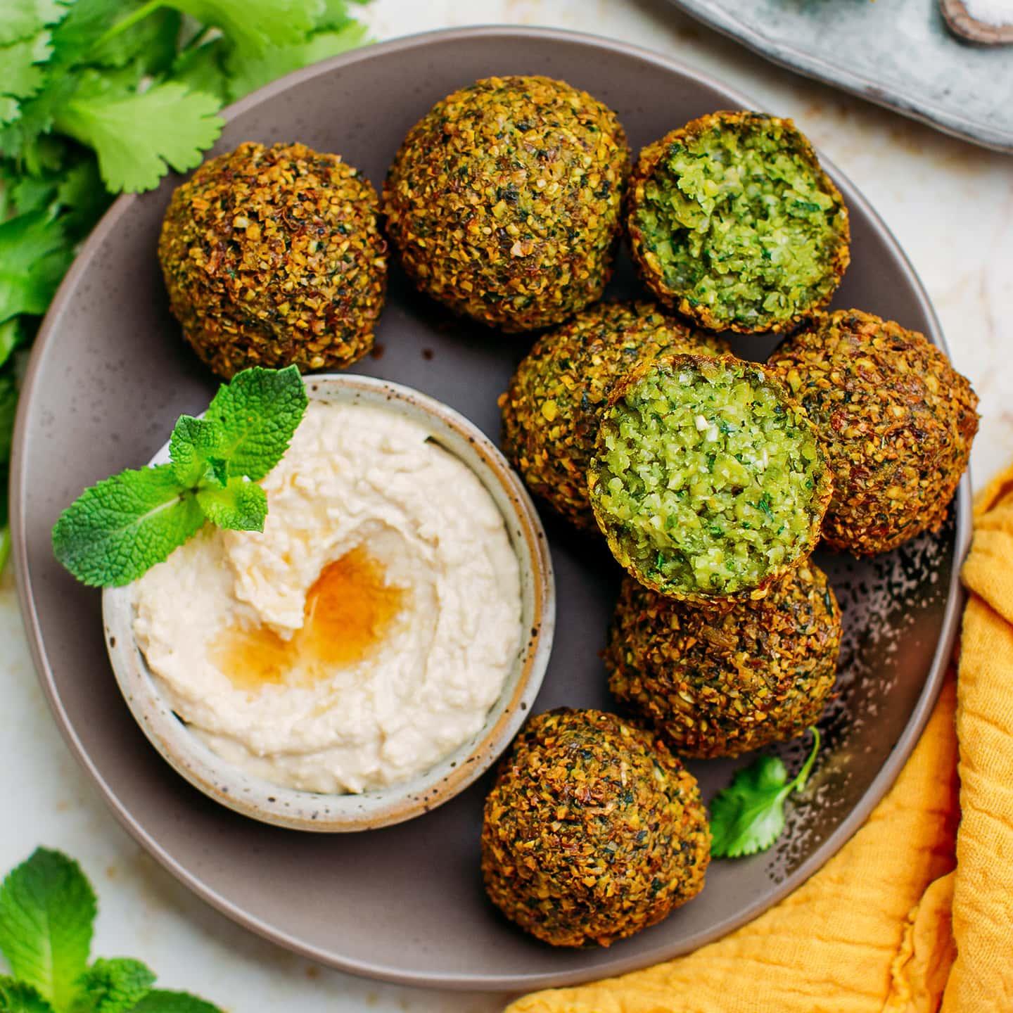 Green falafel balls served with sumac yogurt sauce and fresh herbs