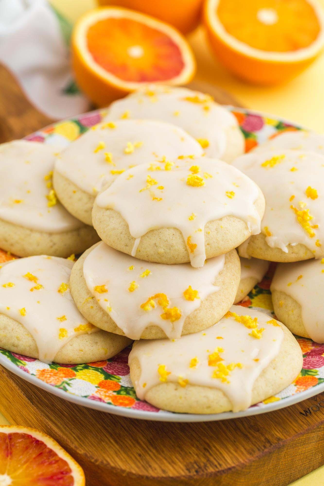 Plate of bright orange zest cookies with fresh orange slices, cozy kitchen background, natural light