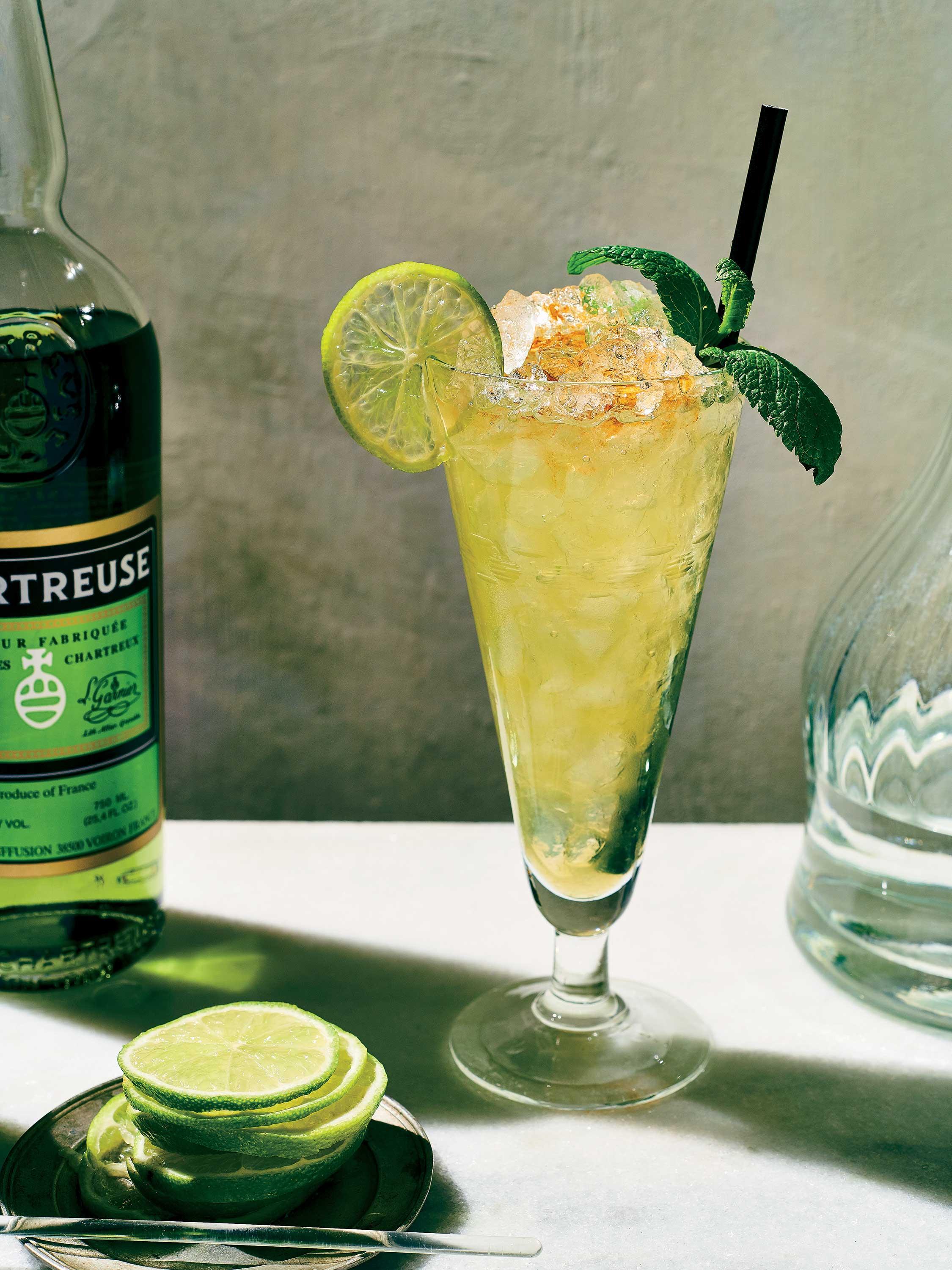 close-up of a person holding a 'Sweet Sixteen Swizzle' cocktail in a sunny outdoor setting