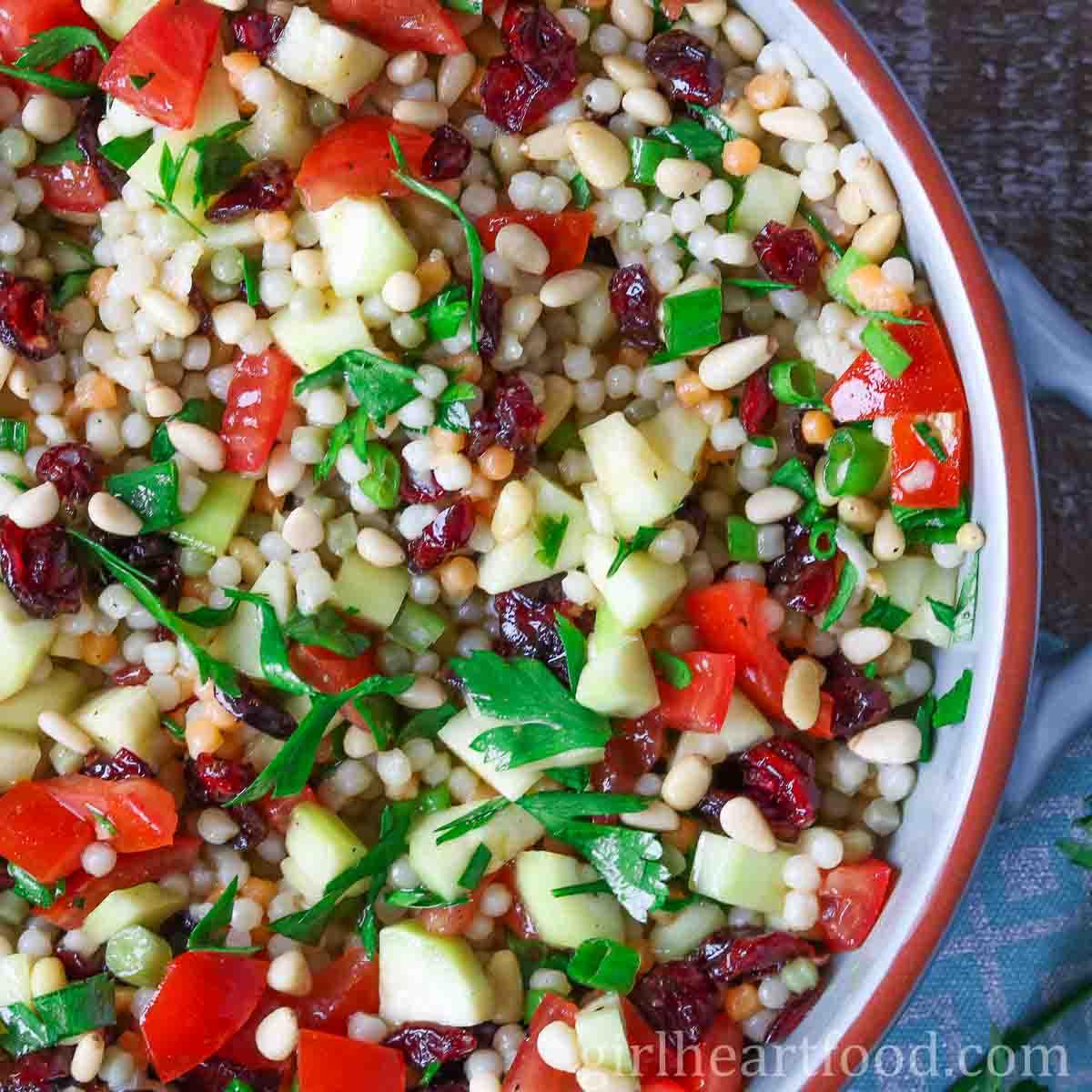 close-up of a bowl of pearl couscous salad being mixed