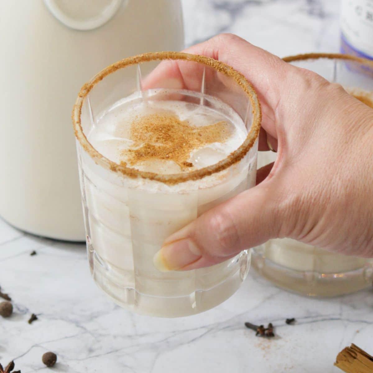Close-up of Coquito being poured into a frosted glass with ice