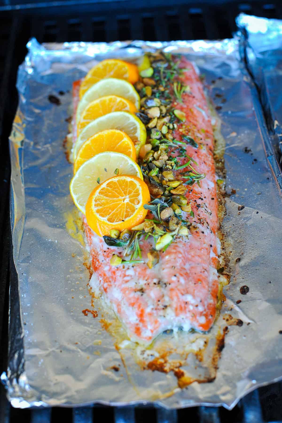 close-up of a hand sprinkling freshly chopped herbs on salmon fillets on a baking sheet