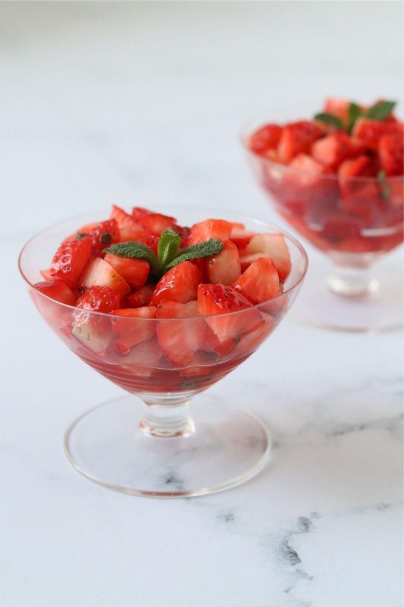 A vibrant and delicious Strawberry Enchantment Salad in a large glass bowl, garnished with fresh mint.