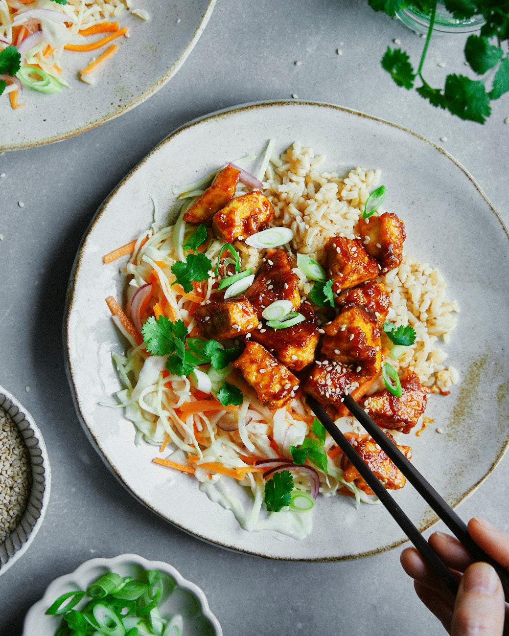Spicy gochujang tofu scramble served in a bowl with rice and sesame seeds