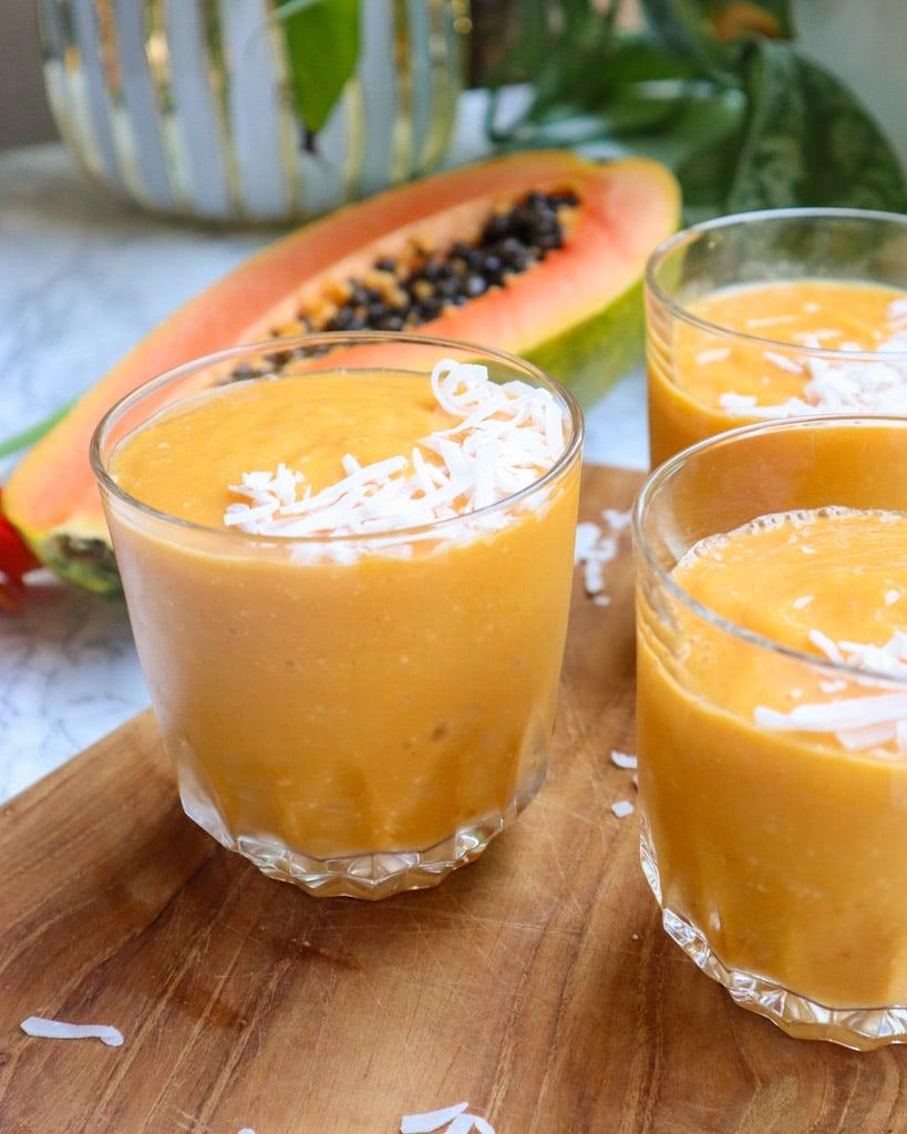 Papaya Orange Ginger Smoothie in a glass with tropical fruits around