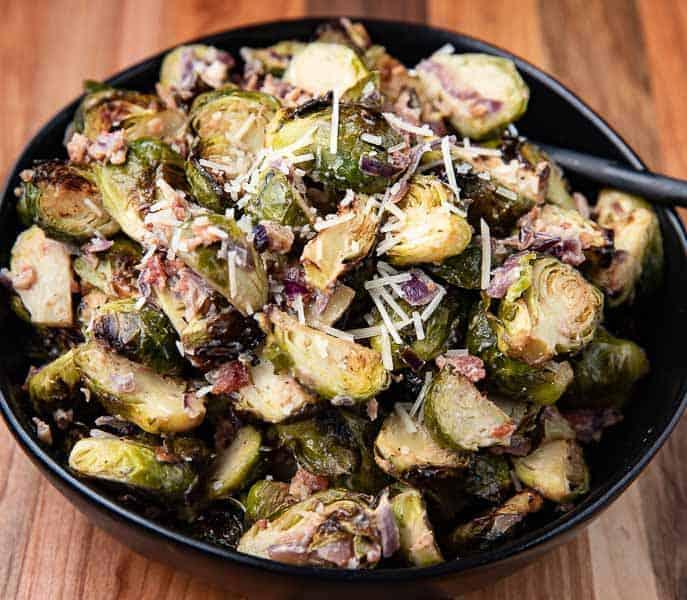 Close-up shot of roasted Brussels sprouts with balsamic glaze, garnished with parmesan cheese