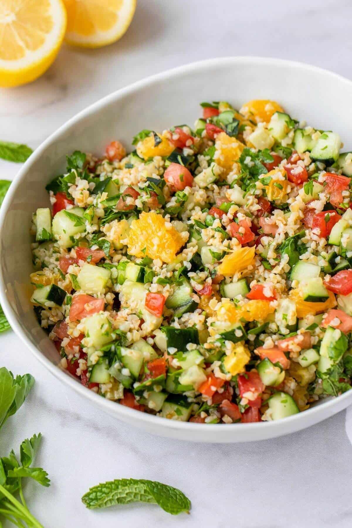 close-up of tabbouleh salad with orange slices and fresh herbs