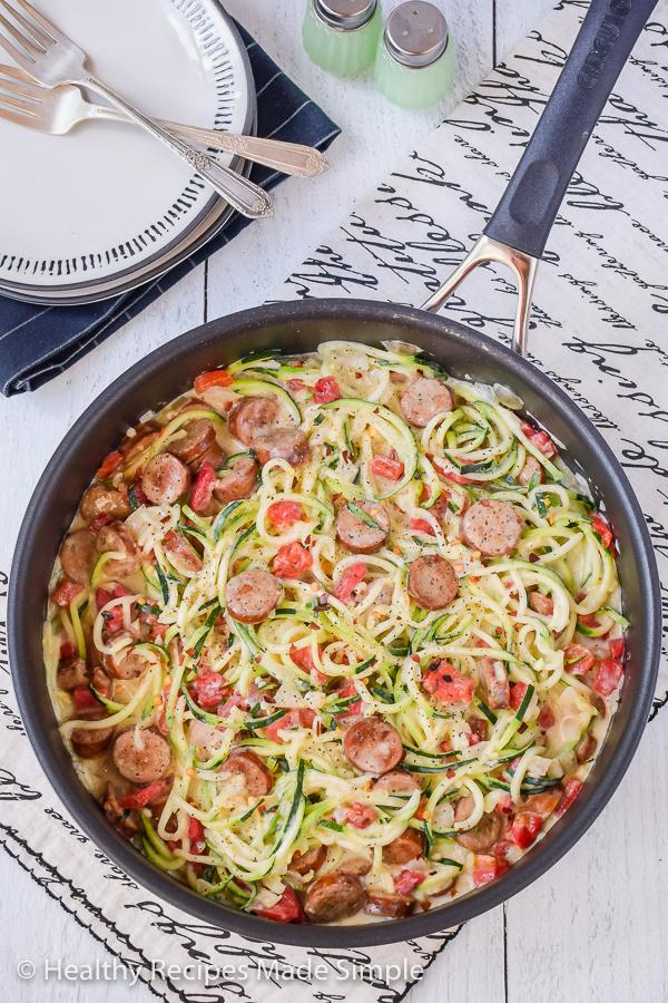 Close-up shot of keto creamy alfredo with sausage and zucchini noodles in a skillet
