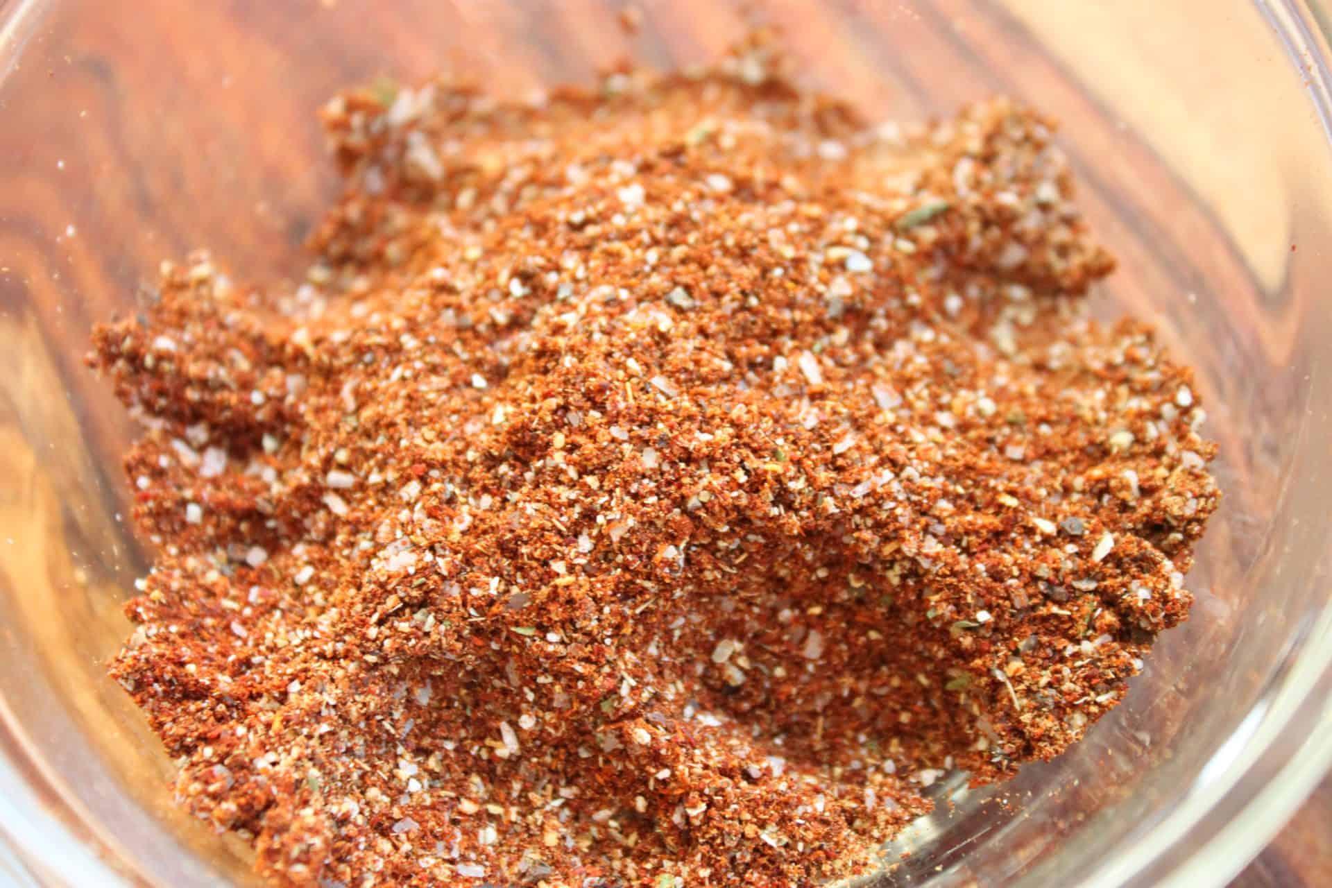 Close-up of spices being added to a pot of chili, showing rich colors