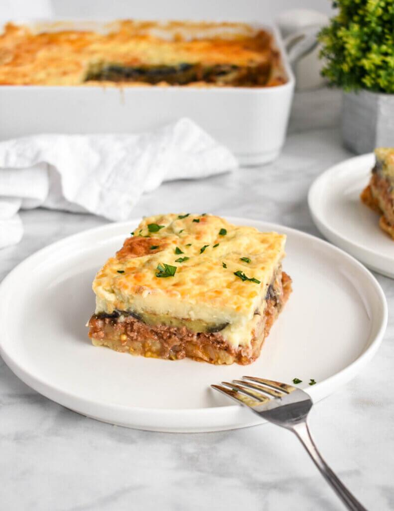 a layered moussaka dish with fresh herbs on top