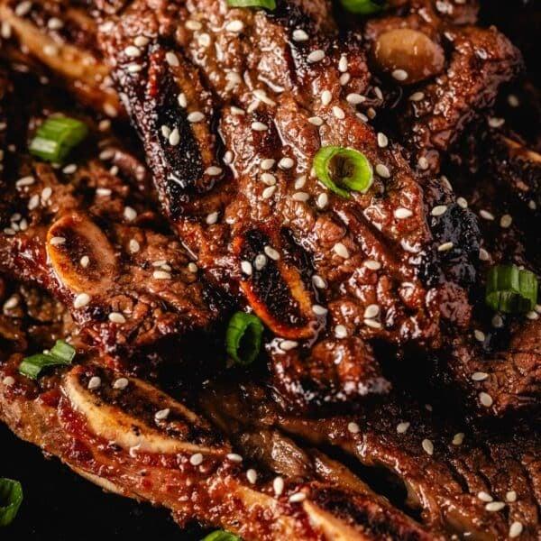spicy korean grilled short ribs on a grill with sesame seeds and green onions