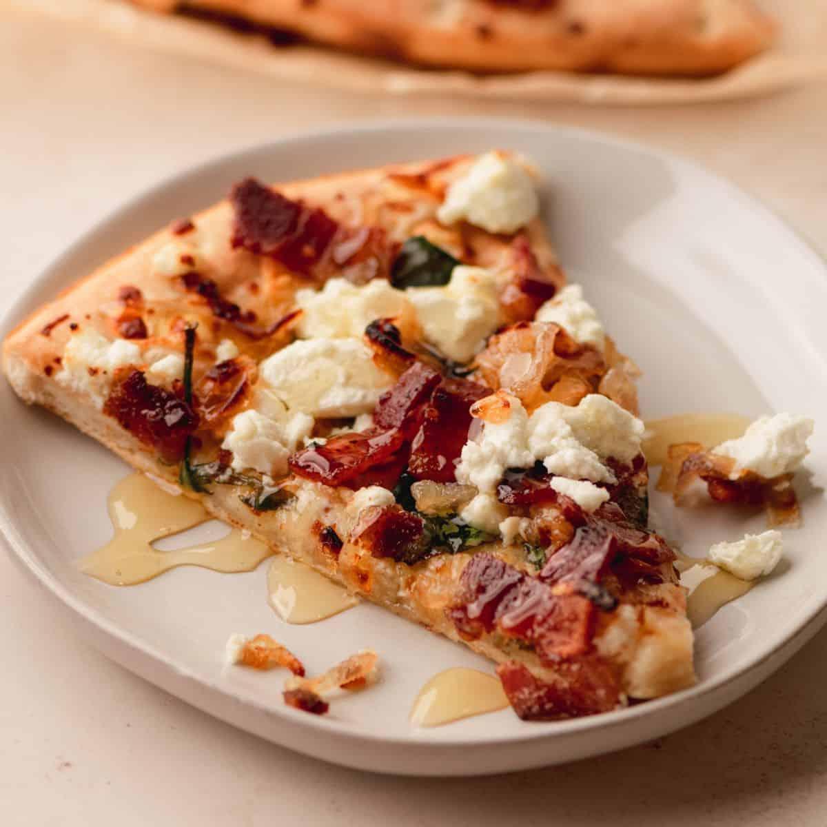 overhead shot of a sliced pizza with caramelized onions, goat cheese, and bacon