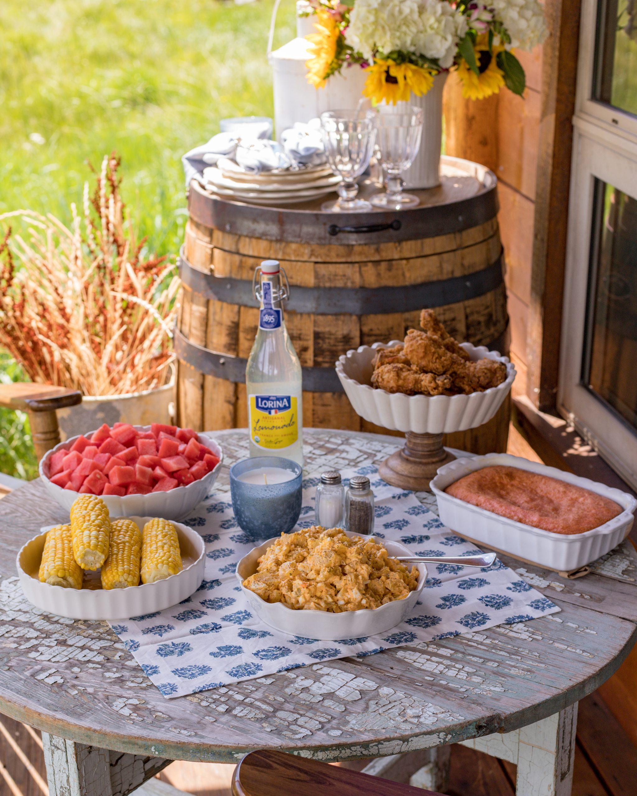 A serving dish of potato salad at a picnic table outdoors