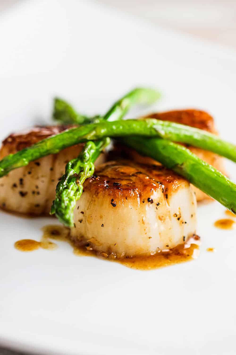 Beautifully plated seared scallops with asparagus and lemon-butter sauce