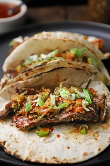 Close up shot of kimchi tacos with slaw, garnished with cilantro
