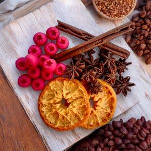 Close-up of cranberries, orange zest, and various spices (cinnamon sticks, star anise) on a wooden cutting board.