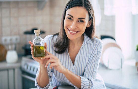 woman smiling holding bottle of olive oil