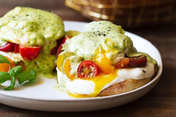 Eggs Benedict with Basil Hollandaise on a white plate, garnished with fresh basil