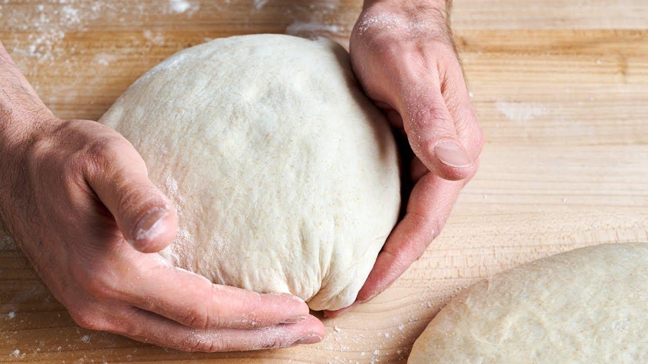 Close-up shot of a baker's hands shaping a sourdough walnut bread dough