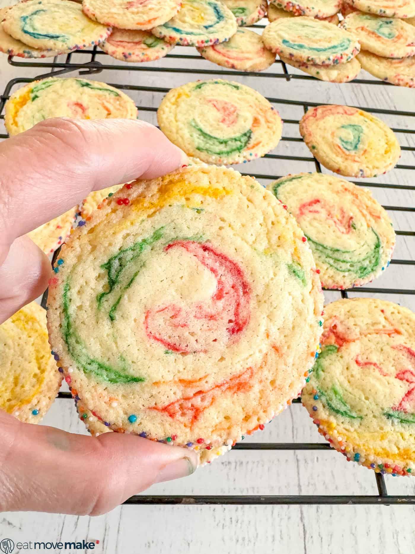 Hands gently pressing two colors of cookie dough together for swirling effect