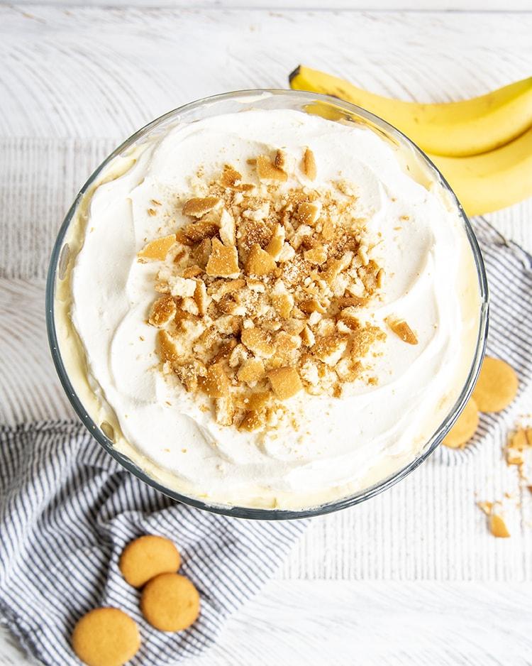 overhead shot of ingredients for banana cream pie trifle, including bananas, vanilla wafers, pudding mix, and whipped cream