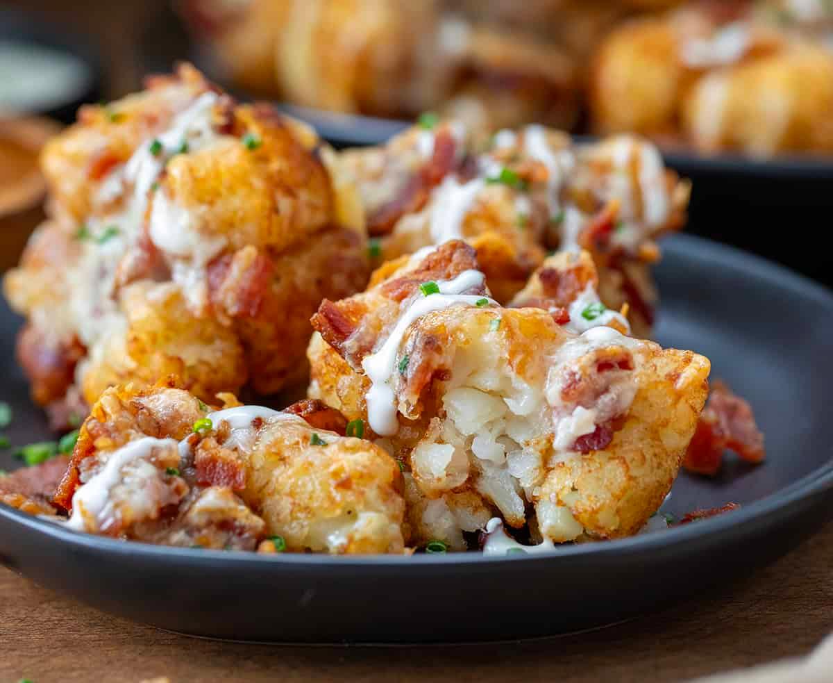 close-up of melted cheddar cheese and bacon bits on golden crispy tater tots