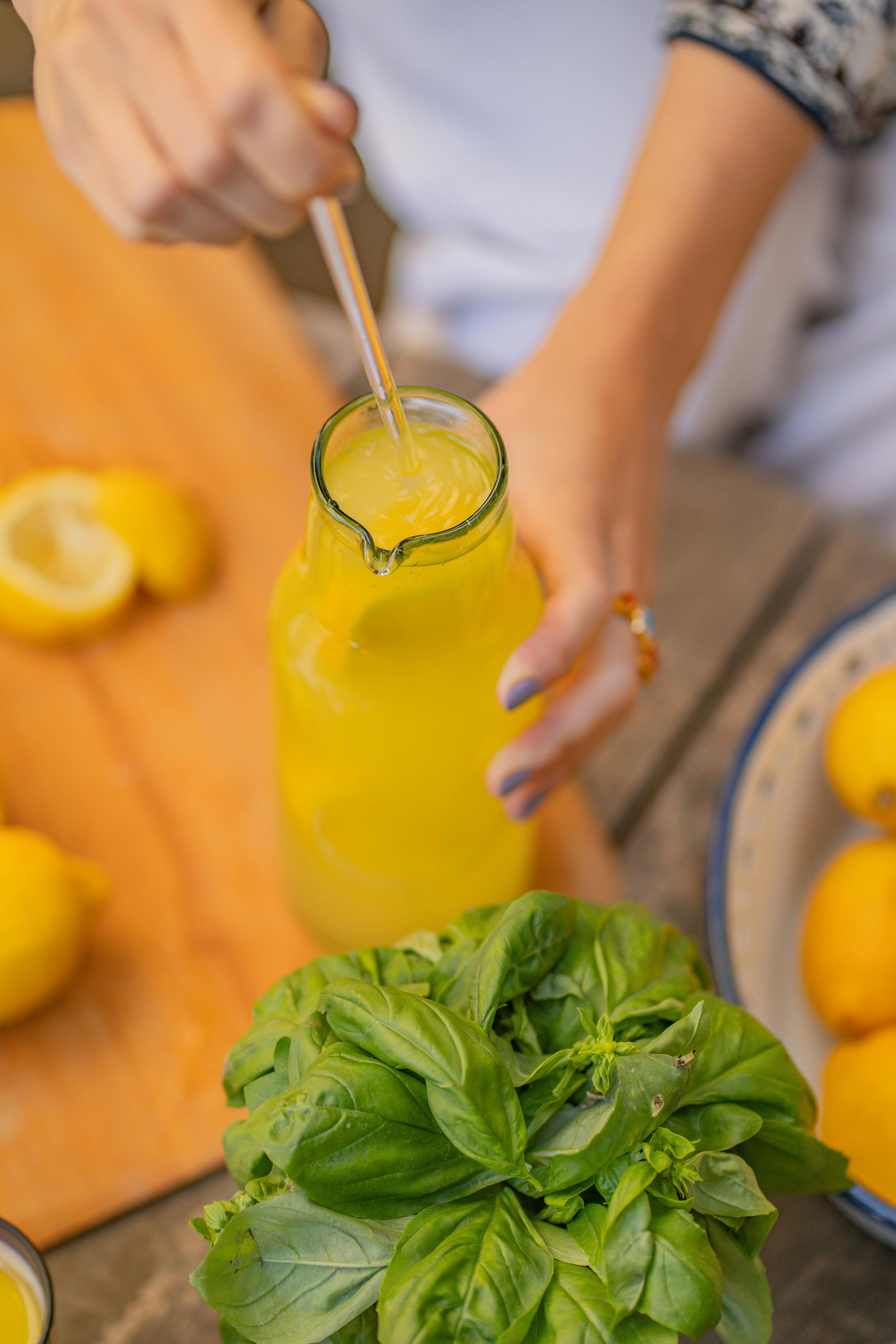 Person pouring a lemon and olive oil smoothie into a glass