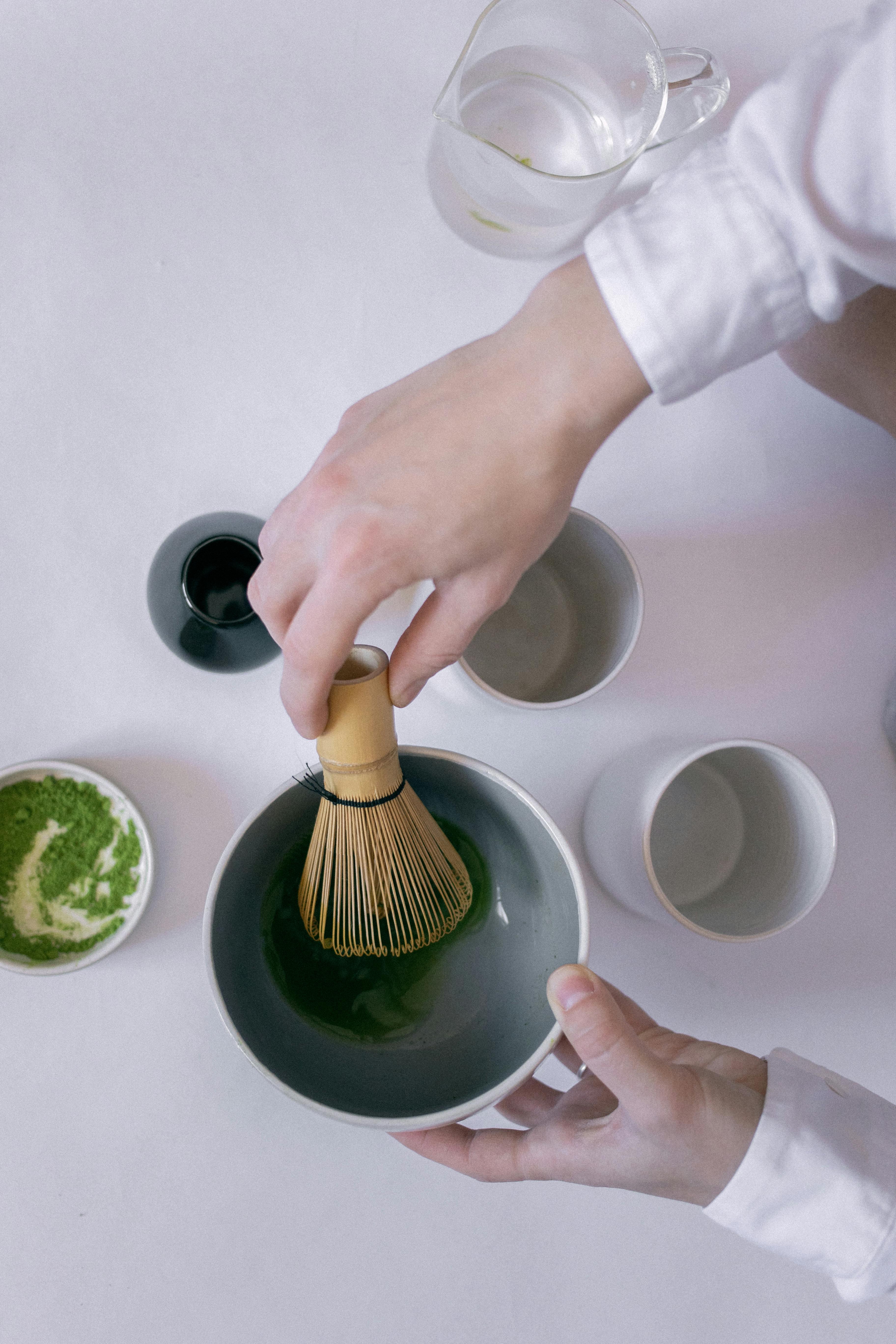 Person preparing matcha in a bowl with a whisk