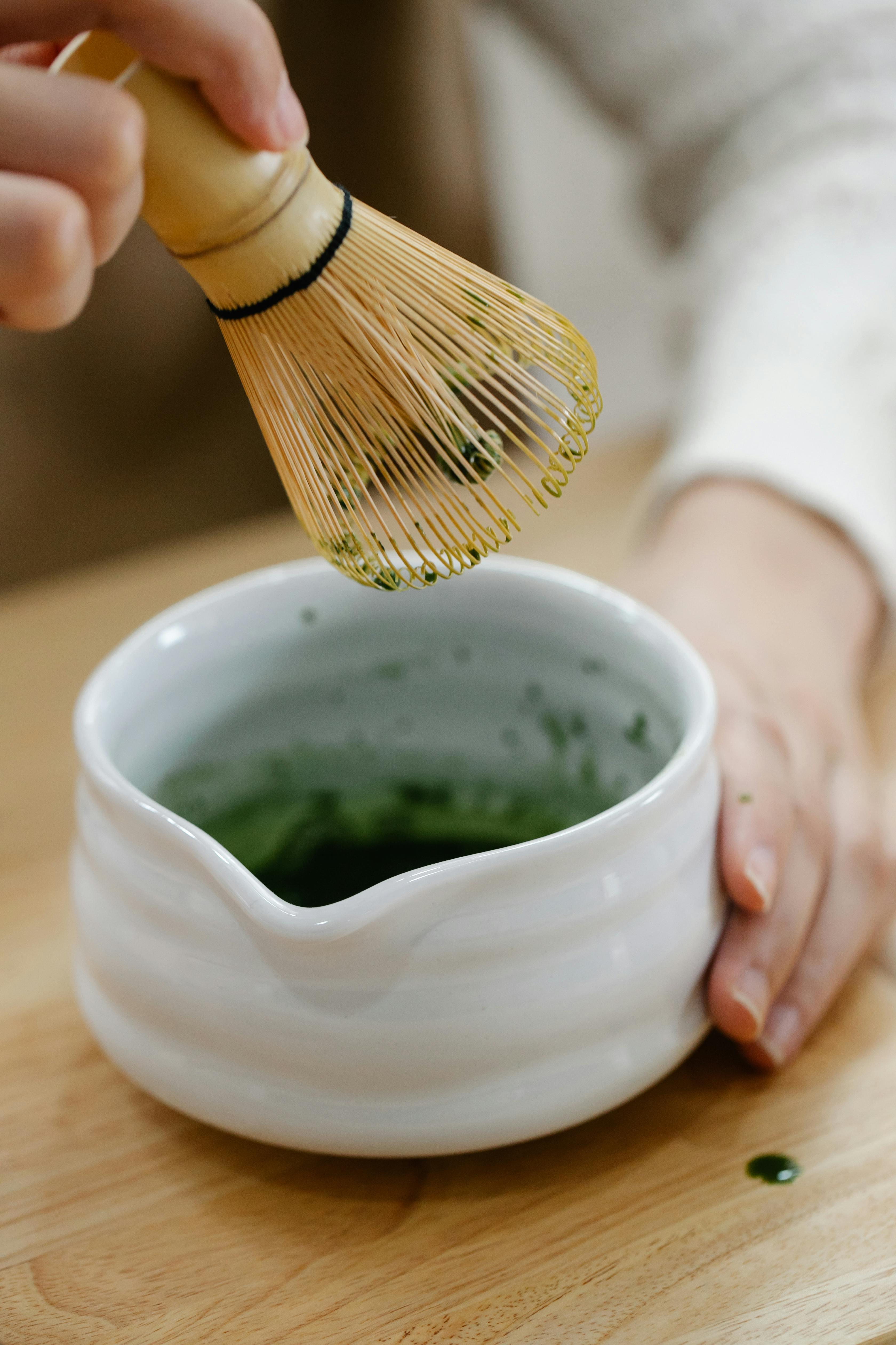 Person holding a matcha bowl and whisk