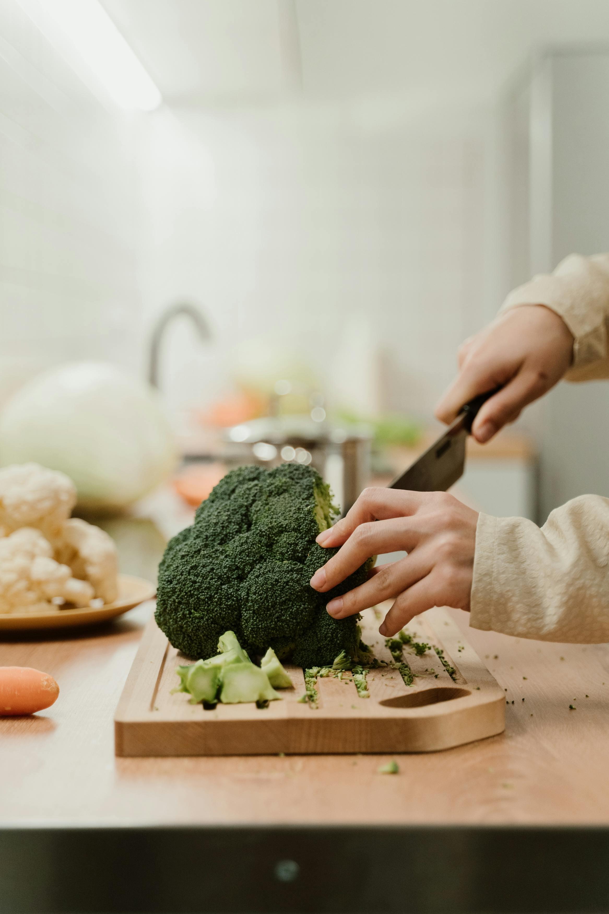 close-up shot of broccoli florets being chopped on a wooden cutting board