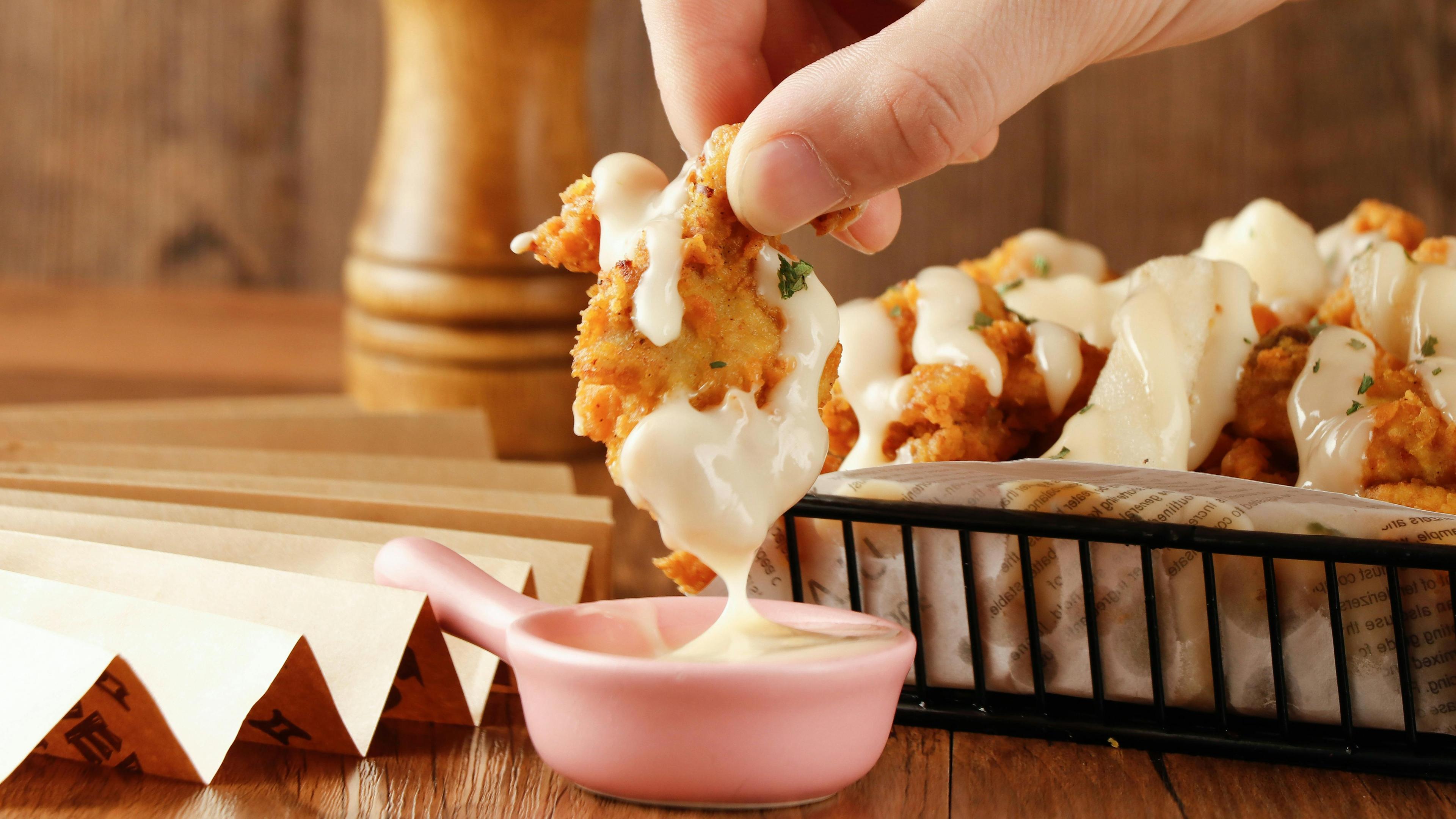 close up shot of crispy vanilla bean fried chicken being dipped in sauce