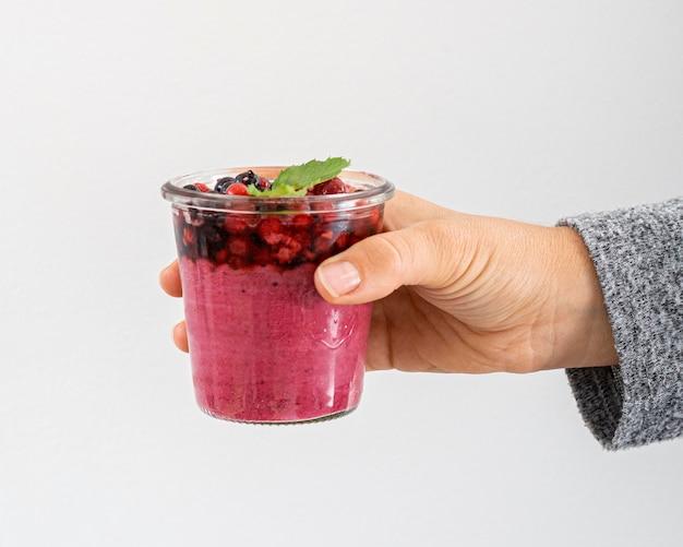 Close up of hands holding a glass of mixed berry smoothie