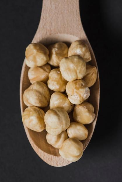 A bowl of roasted hazelnuts with a spoon next to it