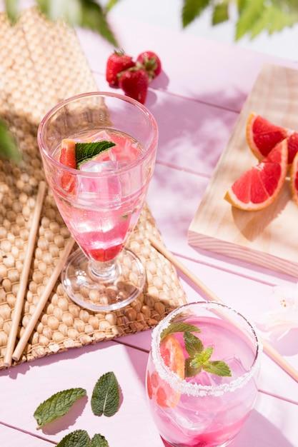 A pitcher of pink grapefruit lemonade with glasses and ice on a table outdoors