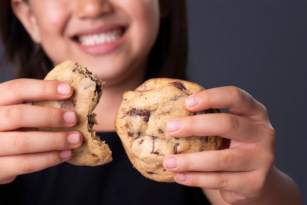 woman smiling while holding chocolate chip cookie