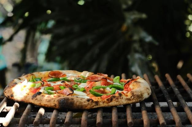 close-up shot of a pizza being grilled on a bonfire