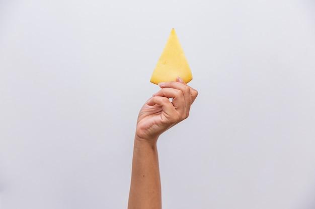 A close-up shot of a hand holding a slice of smoked provolone, showcasing its texture and smoky color