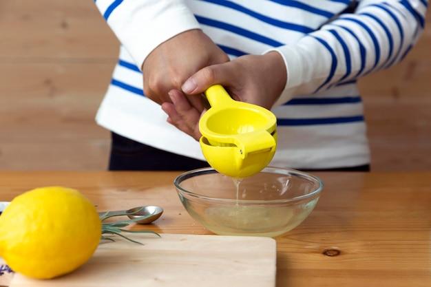 Hands squeezing lemons over a bowl