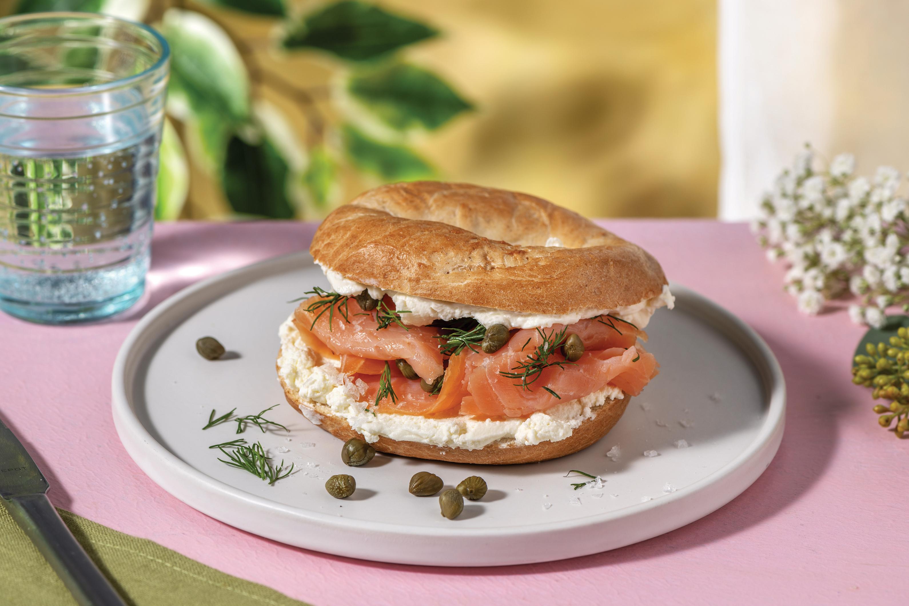 A person enjoying a Smoked Salmon & Dill Cream Cheese Bagel