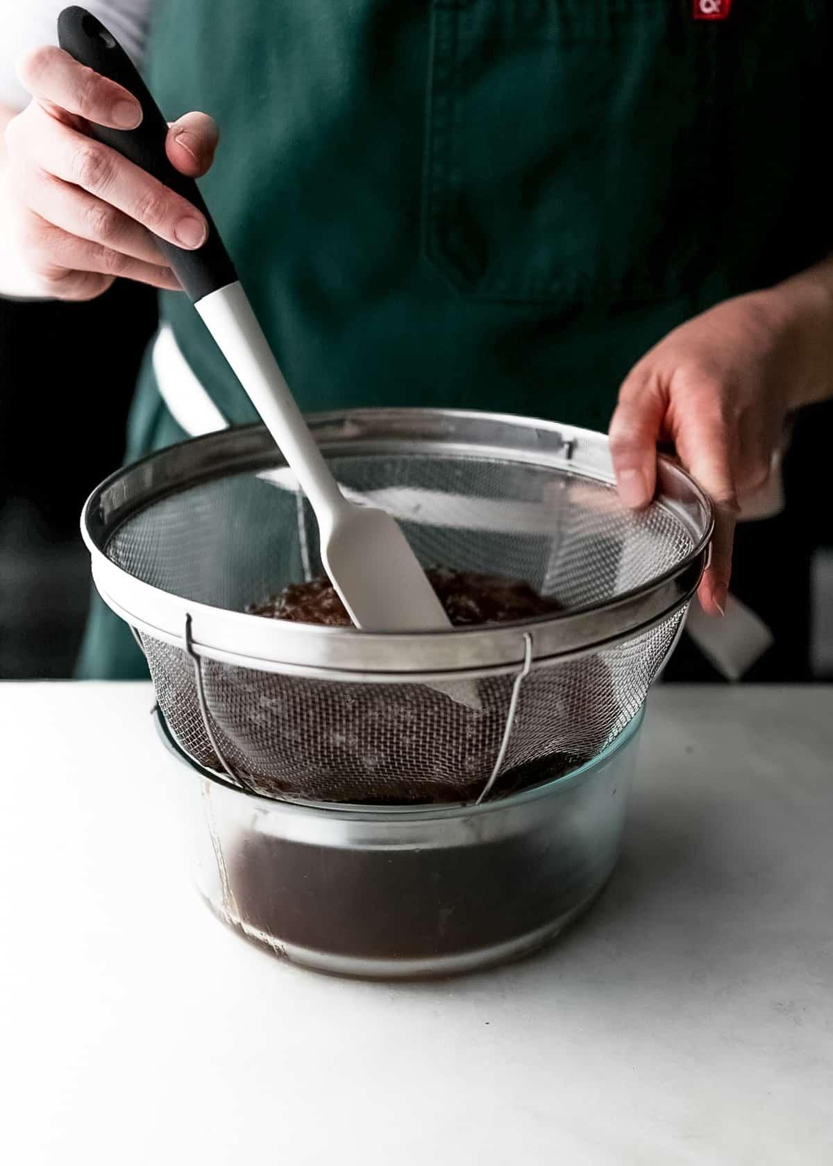 Tamarind paste being strained through a sieve into a bowl