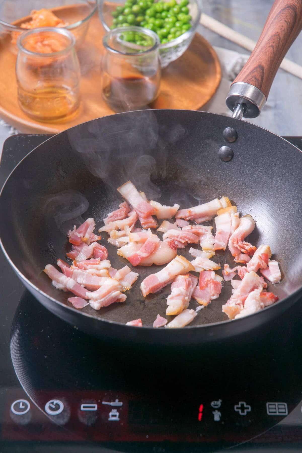 Close-up of kimchi and bacon being cooked in a skillet