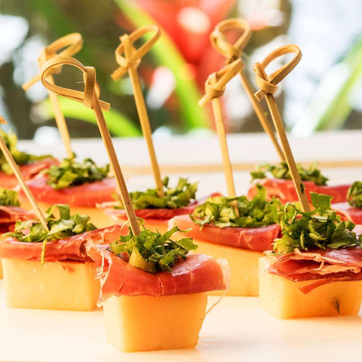 A platter of prosciutto melon baklava skewers served at an outdoor party