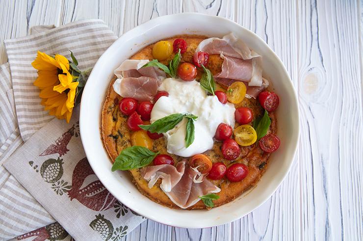 Slices of cherry tomato and burrata frittata on a plate, garnished with basil