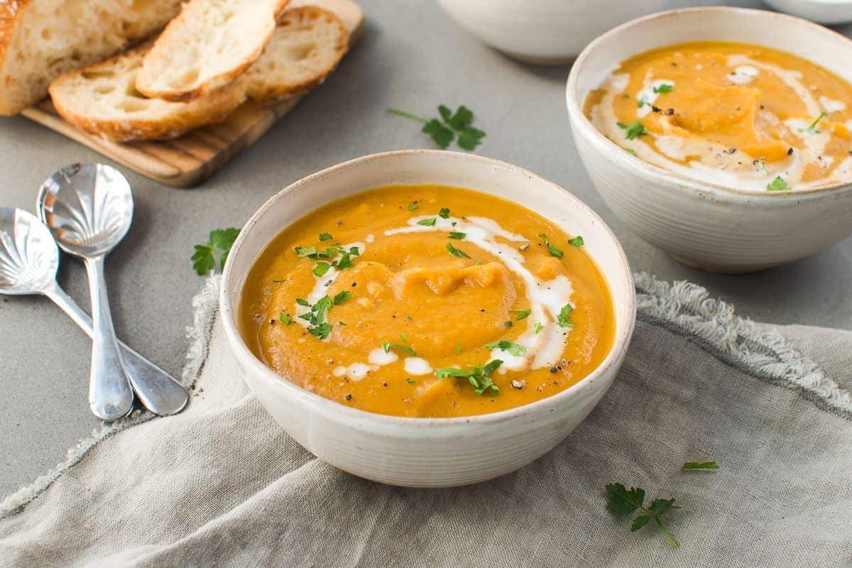 a person serving a bowl of pumpkin and sweet potato soup