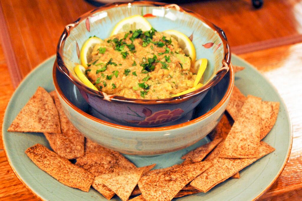 Close-up shot of someone dipping a tortilla chip into Sotol Guacamole