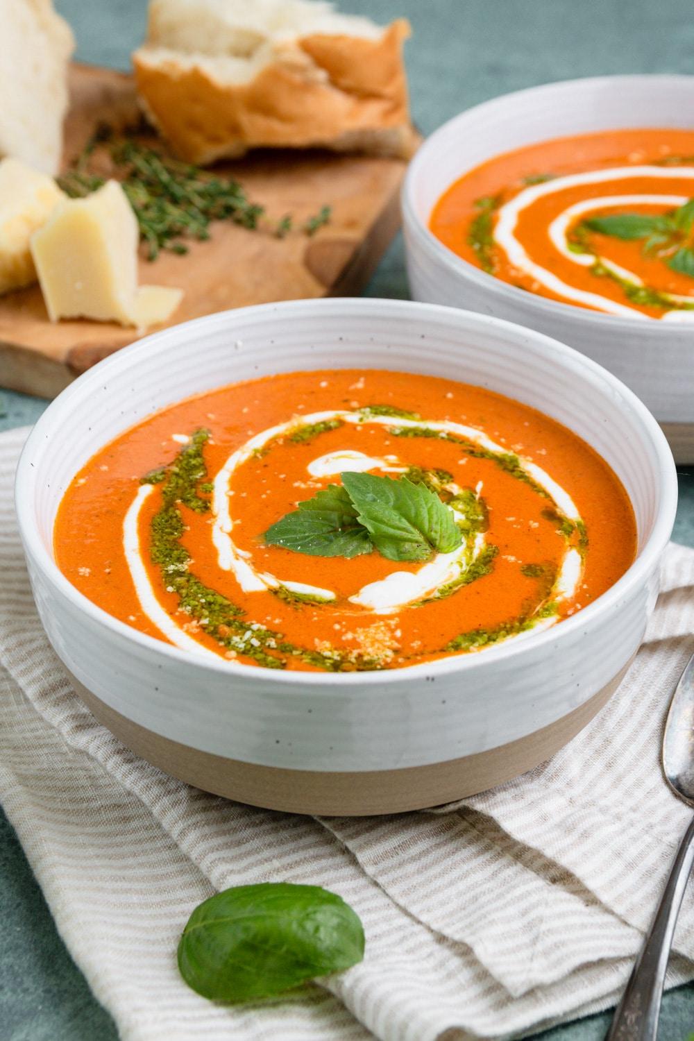 close-up of swirling pesto into creamy tomato soup