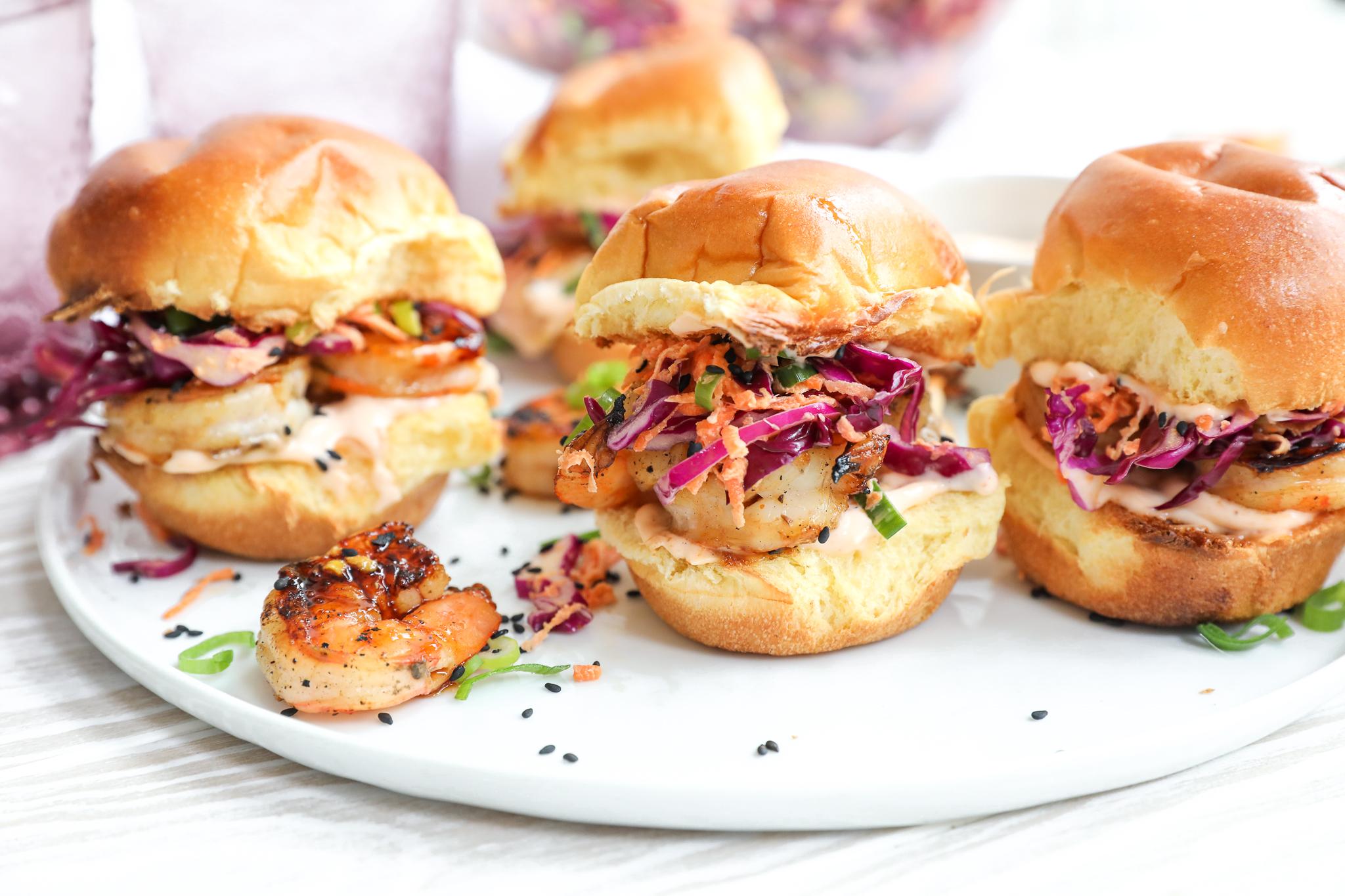 grilled shrimp sliders with fresh toppings on a wooden board