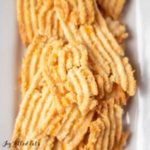 a pile of Wheat Keto Cheese Crackers served on a wooden plate
